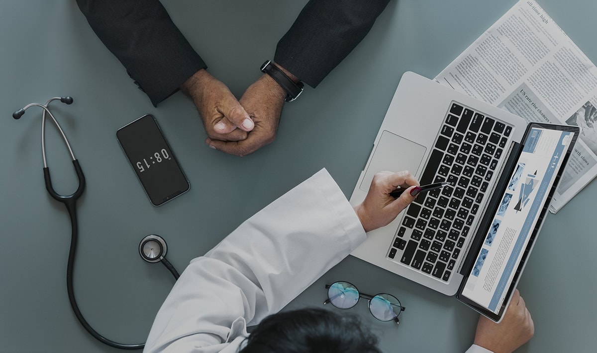 A patient and doctor looking at a laptop